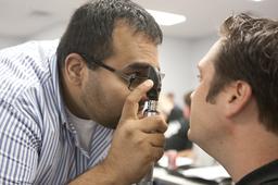 Male nursing student performing eye exam